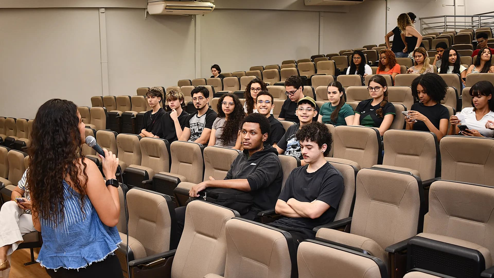Ingressantes sentados em auditório acompanham uma apresentação do Agita Estudantil no Campus Umuarama.